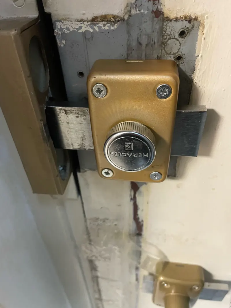 Verrou à bouton monté en applique sur une porte